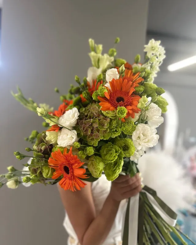 Buchet aerisit cu gerbera portocalie, hortensie verde, eustomă verde și albă, delphinium alb și dianthus